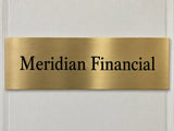 Satin brass door plate etched with Meridian Financial in black, mounted on a painted office door