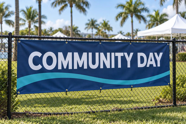 Illustrative custom vinyl banner secured to a fence at an outdoor community event