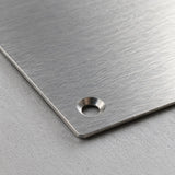 Close-up of a thin aluminum nameplate corner with a drilled and countersunk mounting hole